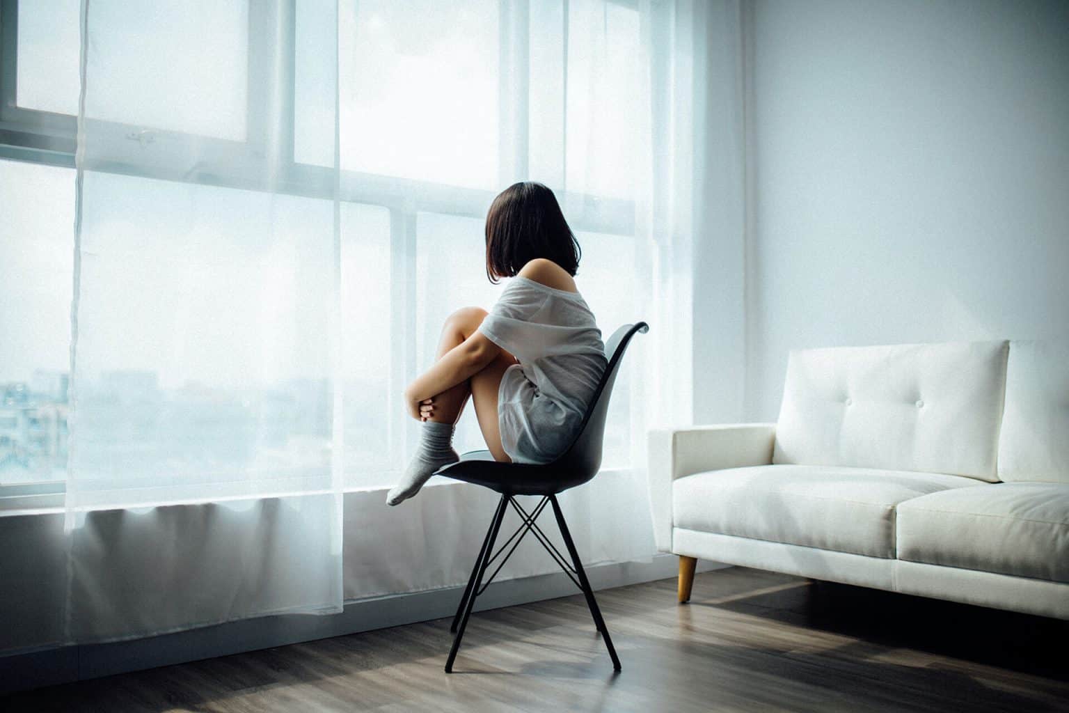 girl sitting on a chair, looking out the window